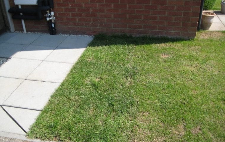 Kensa Ground Source Heat Pump Review: Social Housing - Flagship Housing. The borehole is barely visible in the grass, which has been returfed and paving slabs relaid. - Ground Recovery